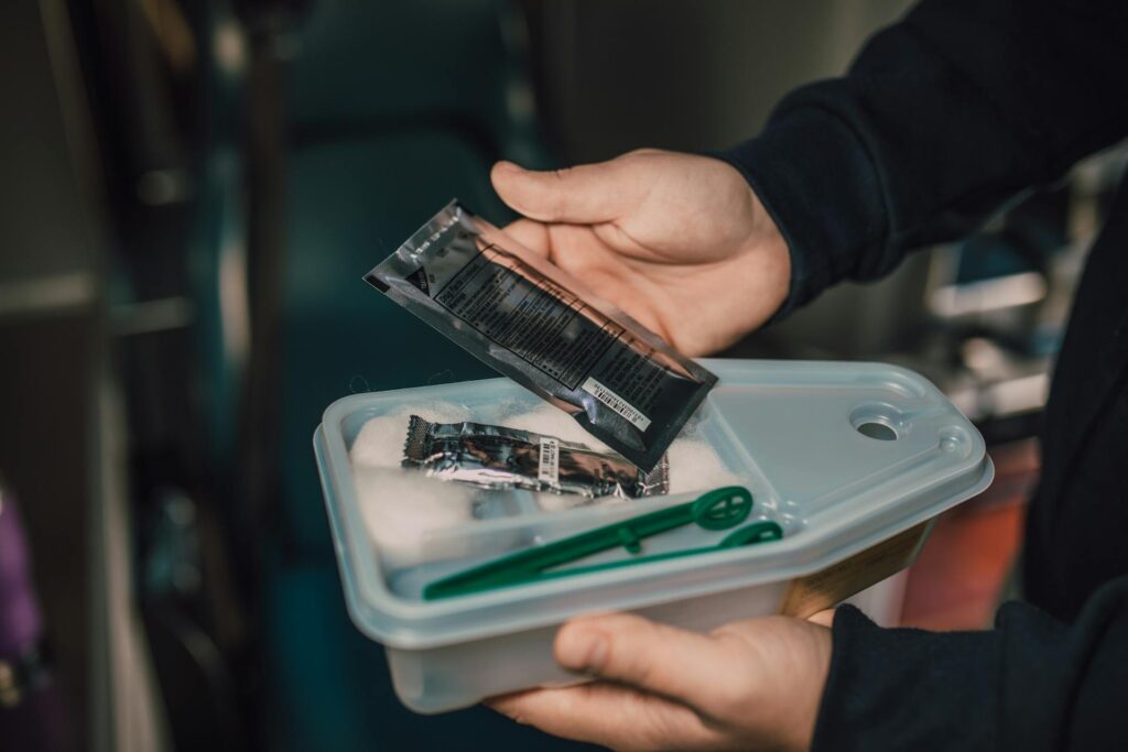 Person Holding a Container With Equipement of First Aid Kits for Offices